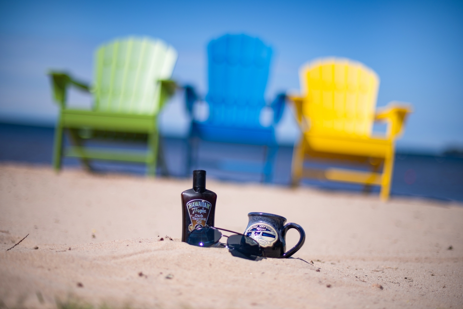 Coffee Mug, Sunscreen, and beach chairs on beach